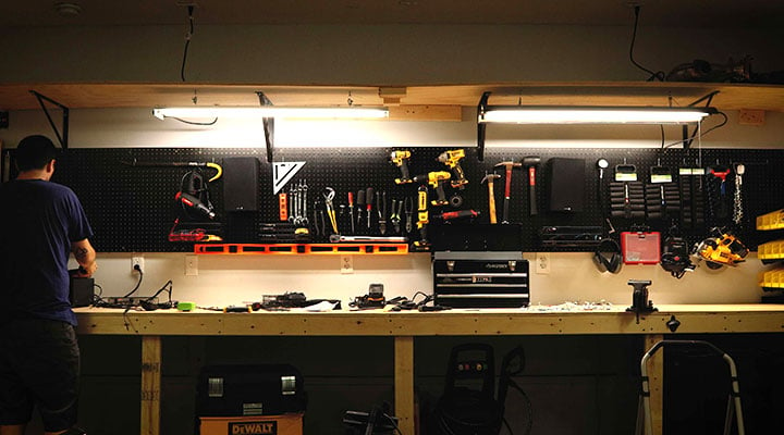 young man organizing tools on his black pegboard storage wall